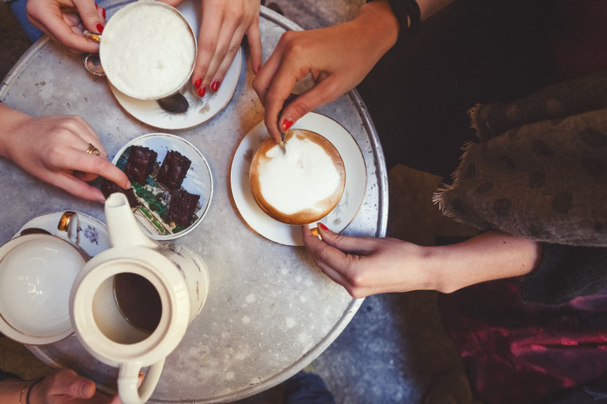 A close-up of three woman drinking coffee around a small table
