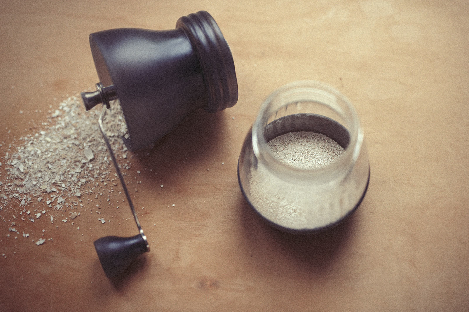 A coffee grinder lies in two pieces with ground egg shell spilling from it