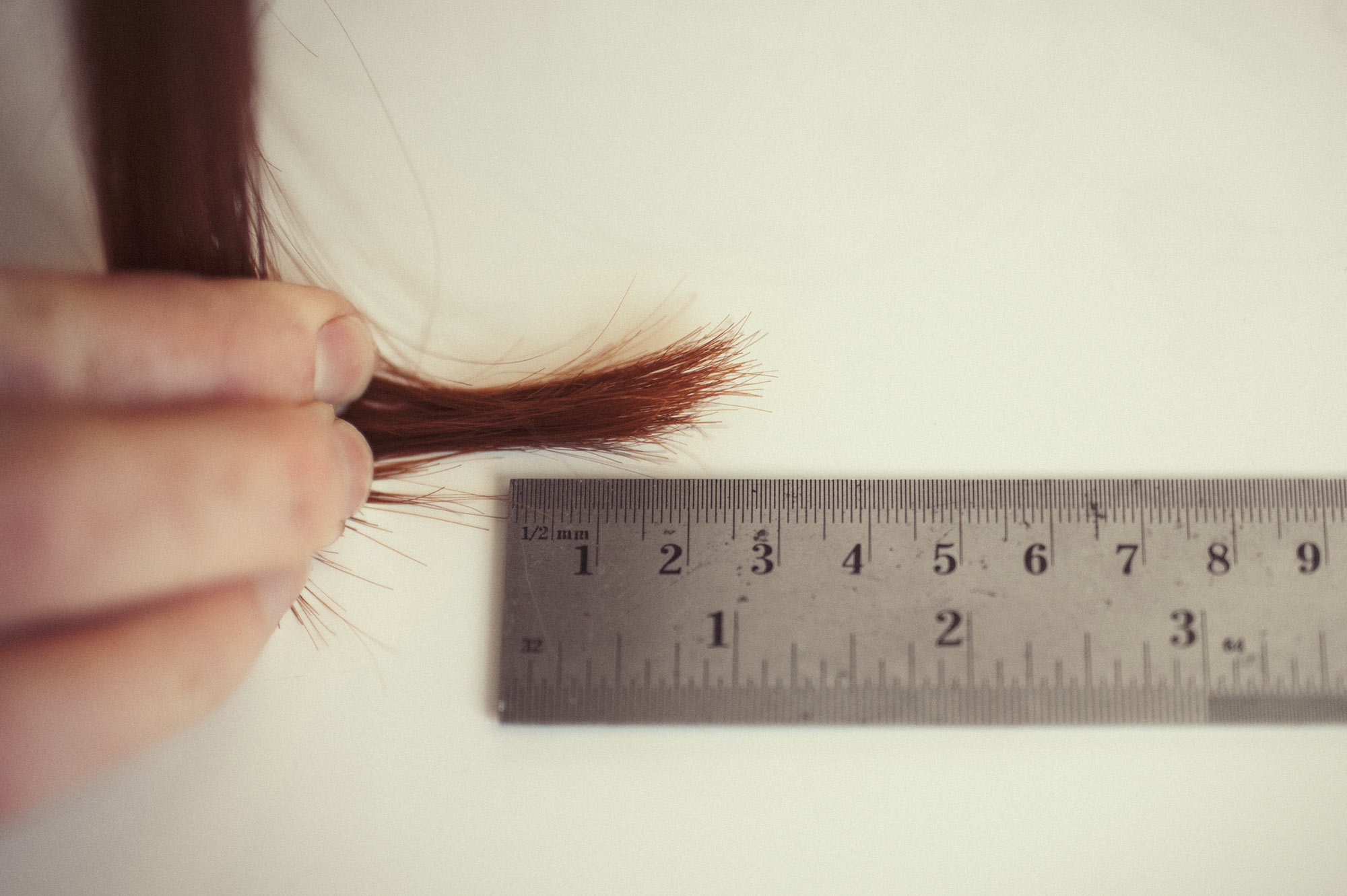 Naturopath Lisa Fitzgibbon displays her red hair against a ruler to indicate how much hair is required for testing