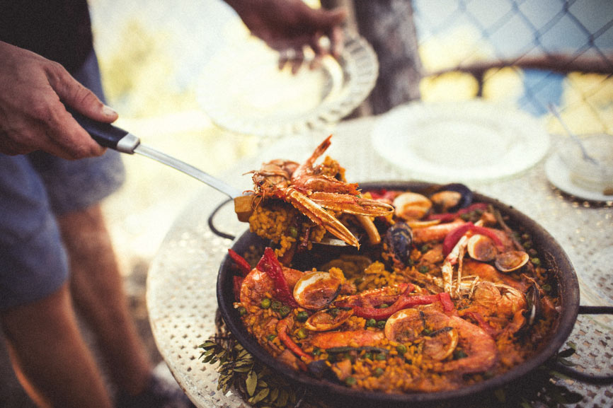 A pan-full of delicious seafood has just been cooked and a man is about to serve it up