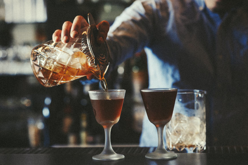 A bartender fills some elegant drinking vessels with some premium spirits