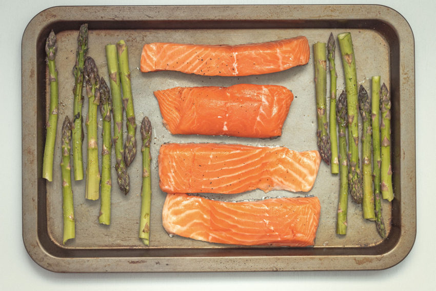 Four pieces of NZ Farmed Salmon and some asparagus on an oven tray